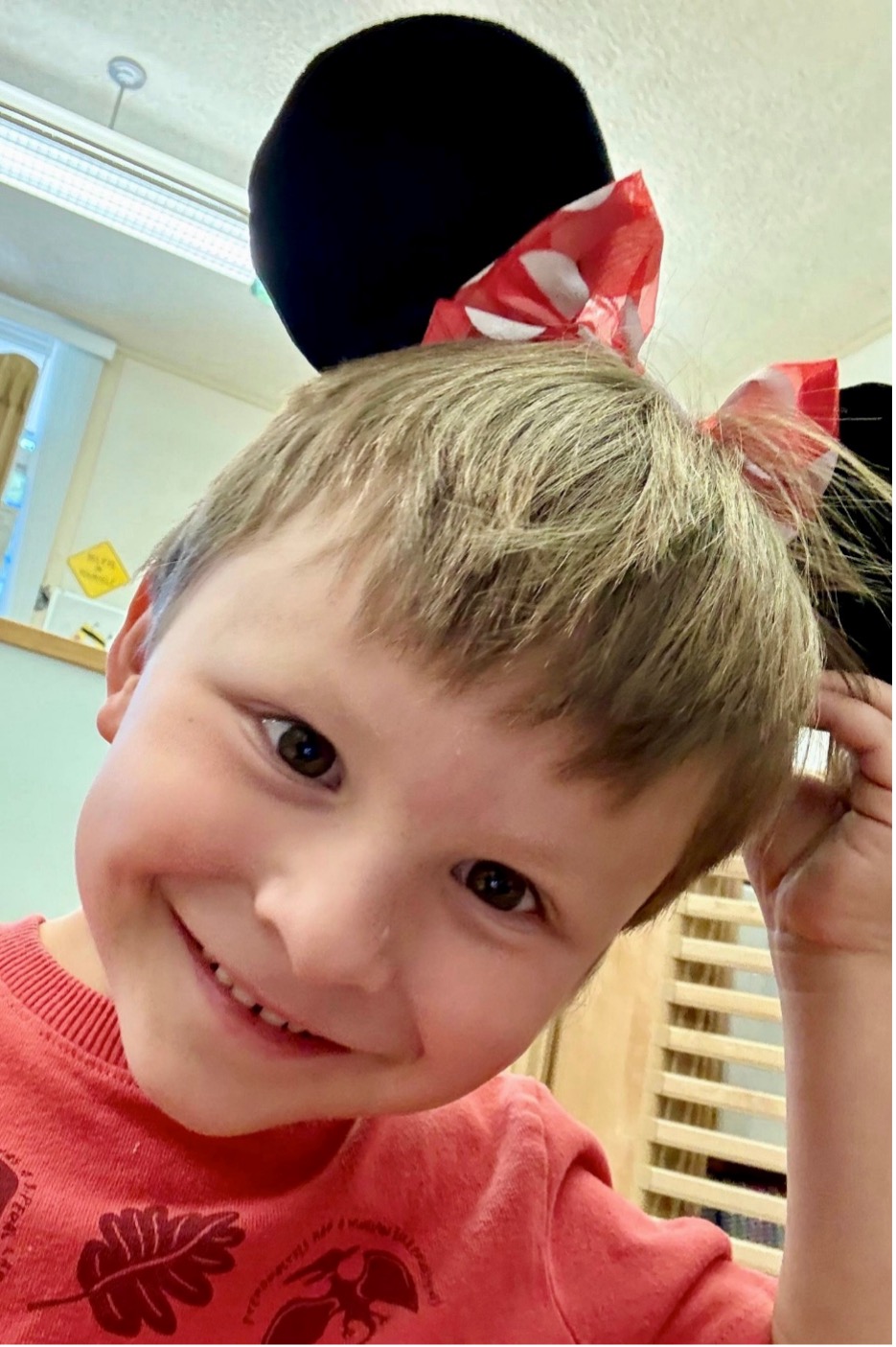 Lucas V. smiles while wearing Minnie Mouse ears in the classroom.