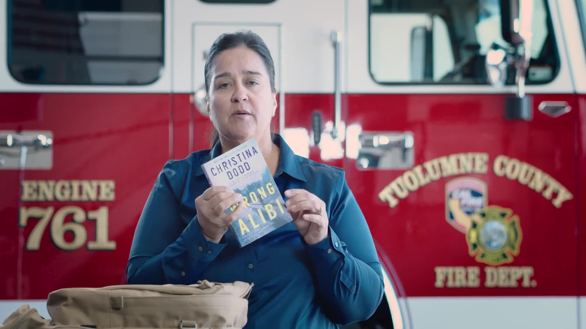 A Tuolumne County firefighter stands in front of a fire engine, holding an emergency “go bag” item during the video Are You Ready? Creating a "Go" Bag.