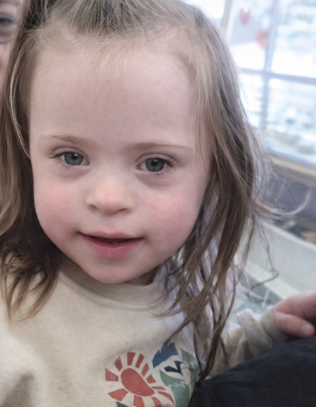 Raven Knutson smiles in the classroom, wearing a light-colored shirt with a small ponytail.