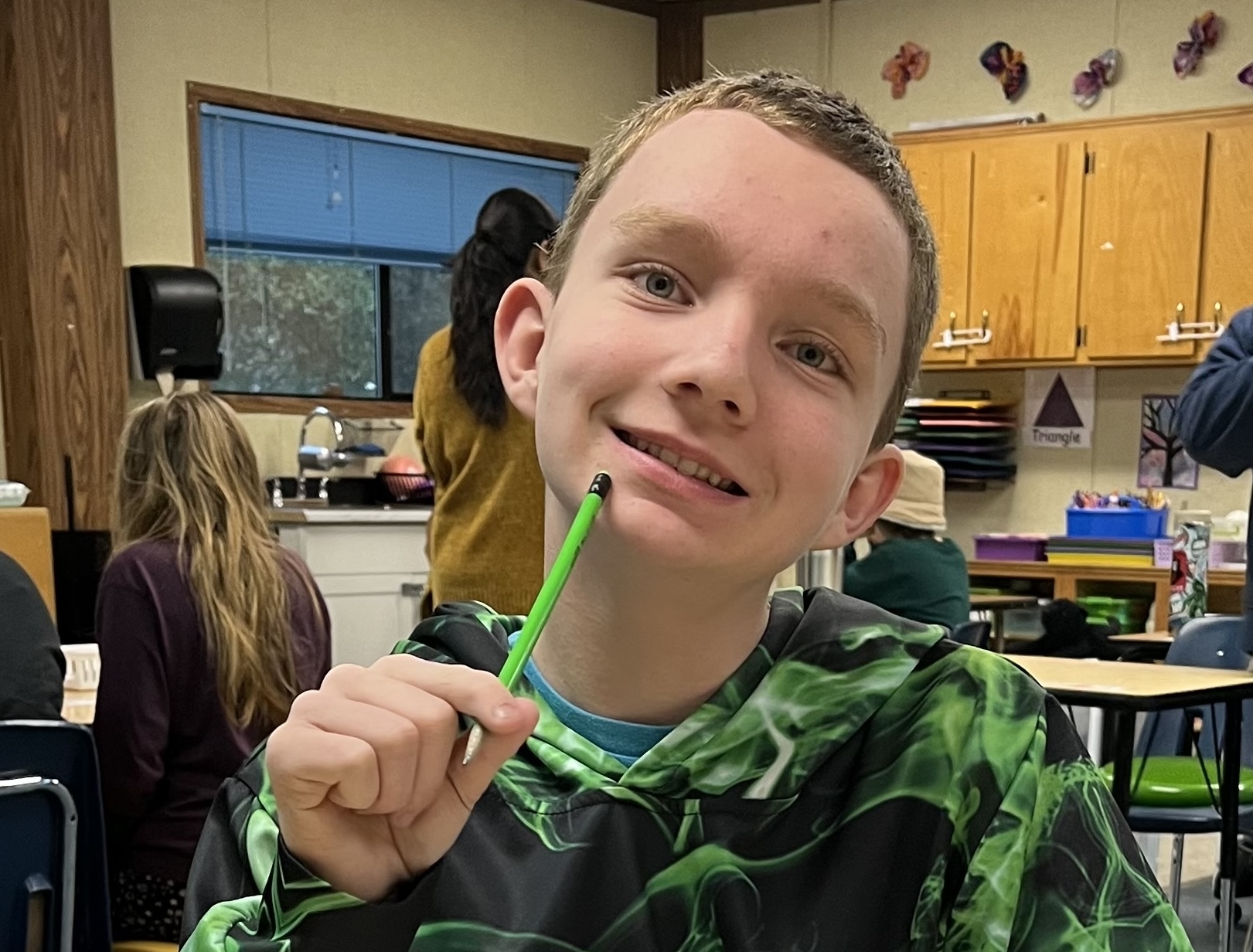 Aiden Carolin Student of the Month March 2026 Aiden Carolin smiles in a classroom while holding a pencil, seated at his desk during class.