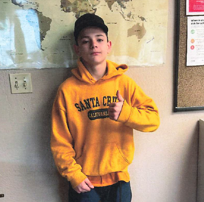 Student of the Month – Michael Agamau Michael Agamau, Student of the Month at TLC Middle School, standing in a classroom and giving a thumbs-up